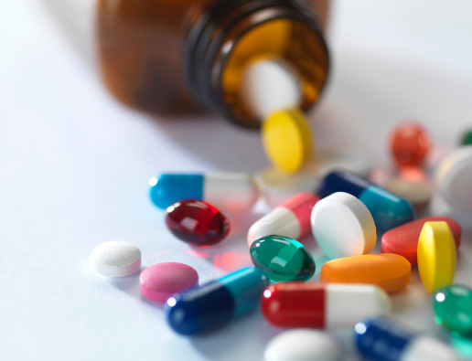 Bottle of pharmaceutical pills spilled on white tabletop 