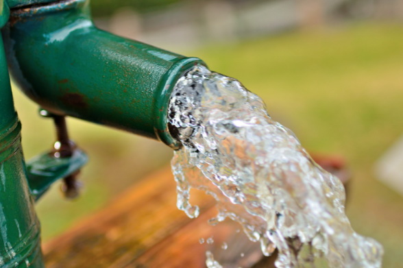 Drinking water pouring out of well pipe